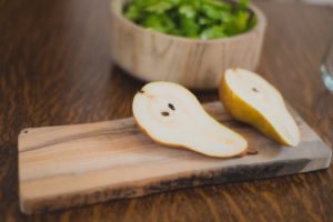 still life of sliced pear and arugula salad in wood bowl