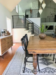 open living and dining with second story and black metal horizontal staircase railing