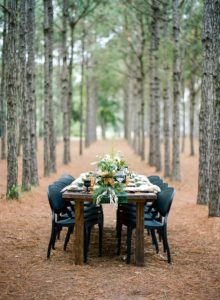 glam black and green holiday party table in the woods