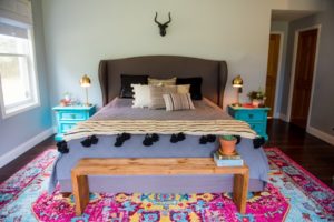 modern boho master bedroom with bright rug and vintage night stands